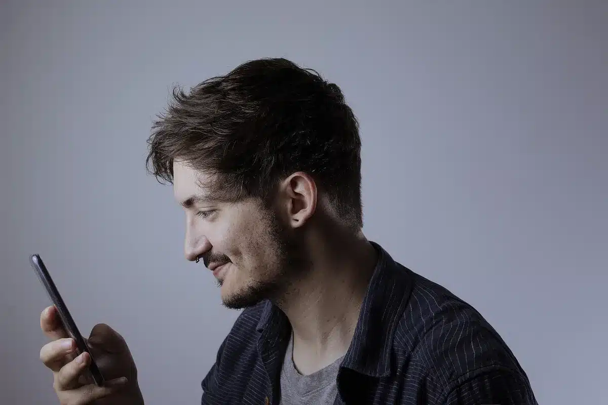 Over-the-shoulder view of anonymous hands holding a phone while tapping a stickers menu in a chat composer, showing a selection of generic circular music icons, no brand or faces