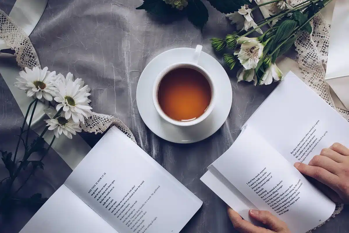 anonymous empty reading nook with a small table, an open notebook and a steaming cup, soft morning light