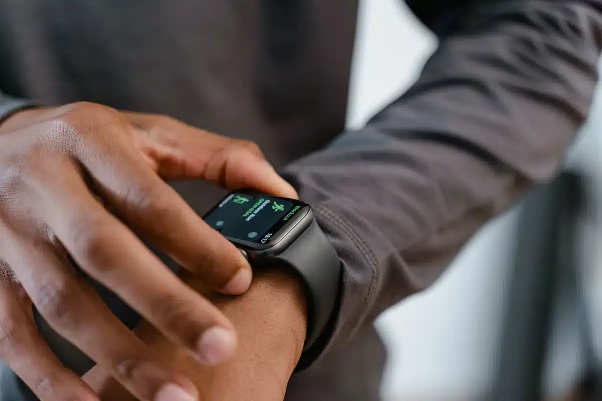 A close-up of an unbranded premium smartwatch on a neutral surface, titanium case and rubber strap visible, screen off showing reflective glass