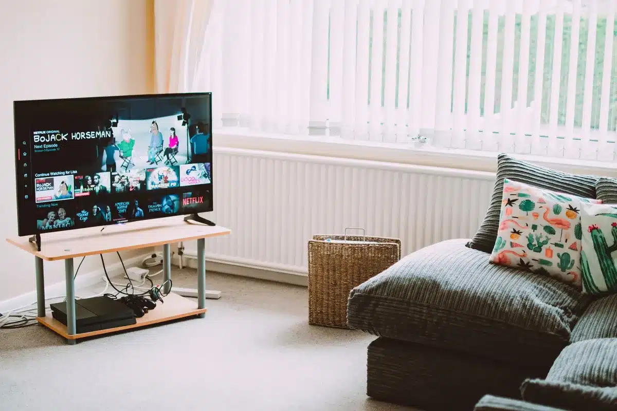 Wide living room scene with an anonymous large 75-inch TV on a stand, soft evening light, no logos; living room decor hints at a recent purchase